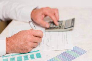 Professionnel calculant et remplissant une facture d'électricien avec un stylo et une calculatrice
