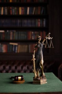 Dame Justice et marteau sur une table dans un cadre de bibliothèque de droit classique.